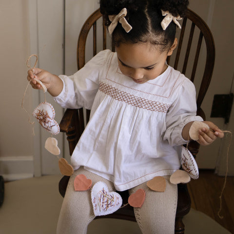A young child holding a handmade Valentine Garland. Valentine's crafts for kids.