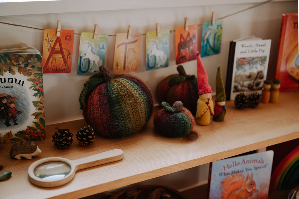 Seasonal elements like knit pumpkins sitting ontop of a toy shelf