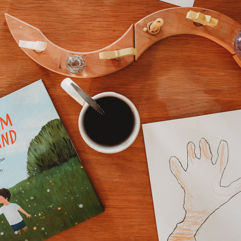 a childs hand traced on a piece of drawing paper next to a cup of tea and a picture book