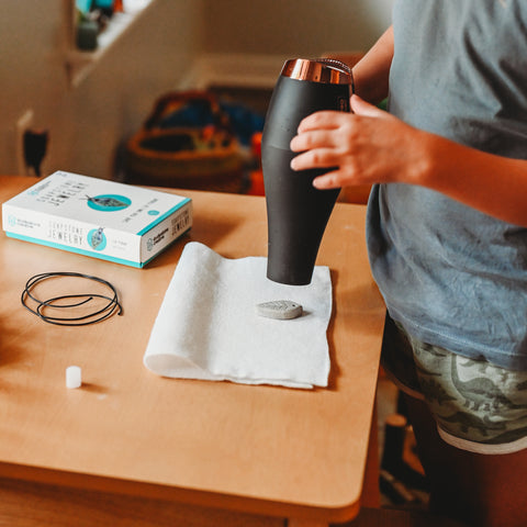 A child holds a hair dryer to a piece of a soapstone to warm it