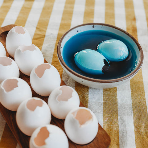 Two egg shells in a blue natural egg dye bath.