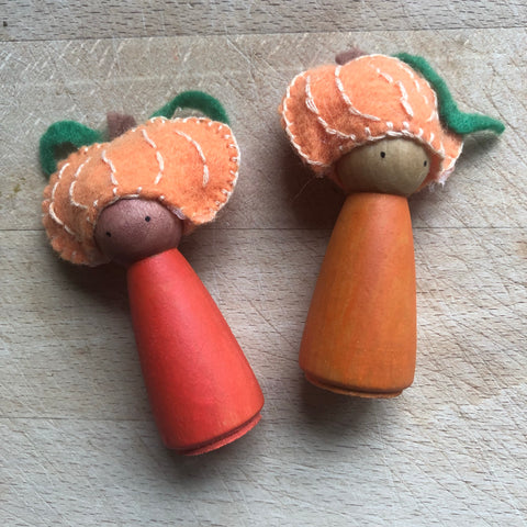 Two orange and brown peg dolls with felt pumpkin hats wooden toy tutorial