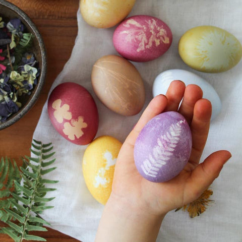 A childs hand holding a floral printed Easter Egg
