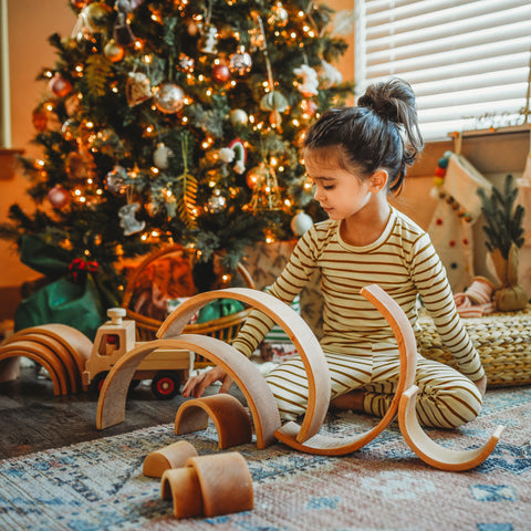 Playing with Grimms Natural Rainbow by Christmas tree.