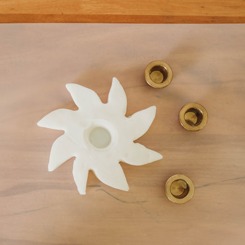 Brass candle holder birthday ring inserts next to a sun made of clay