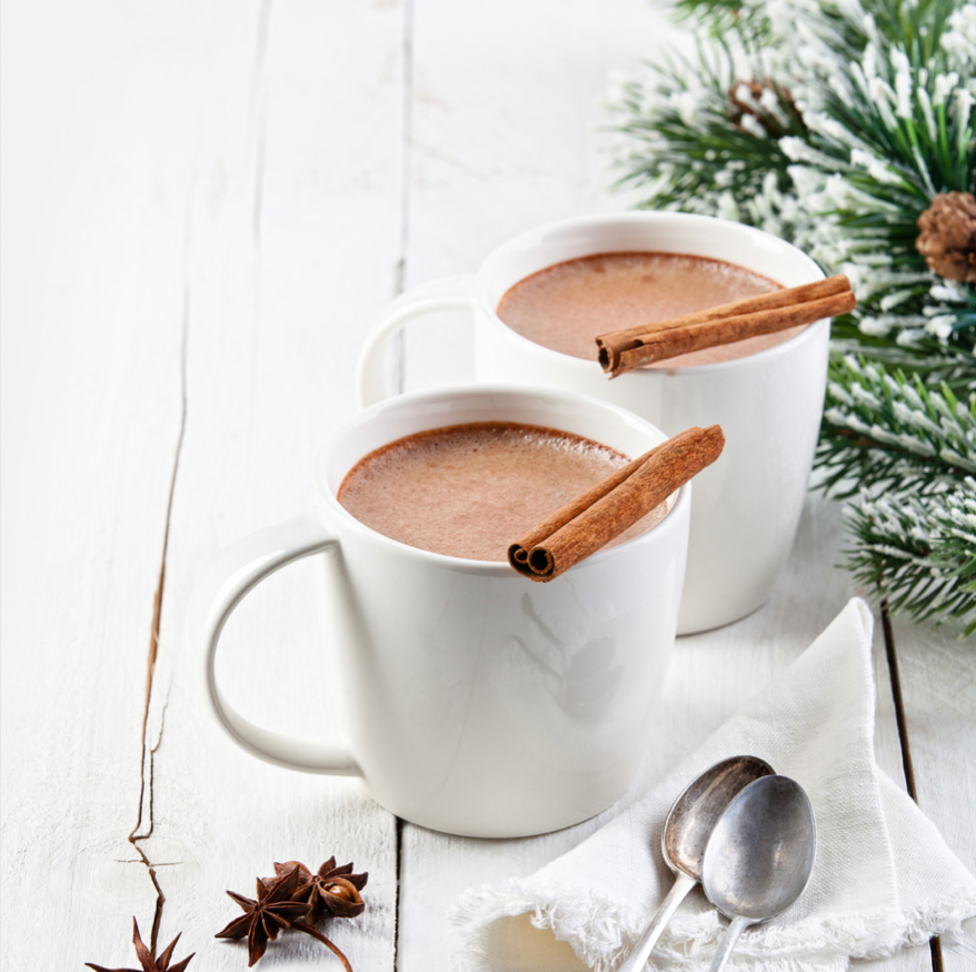 Two cups of hot cocoa with cinnamon on the rim