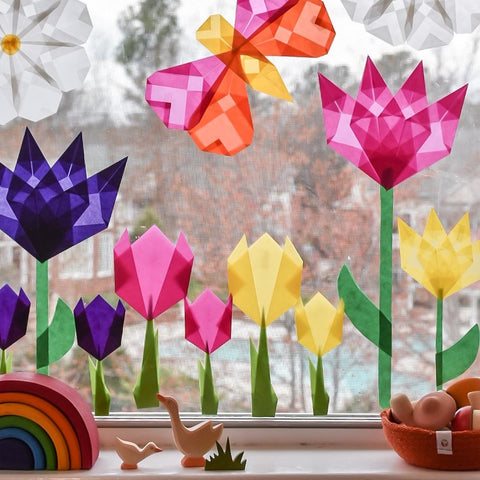 Waldorf window star flowers decorating a window with wooden toys on the window sill like a small Grimm's rainbow and ostheimer geese