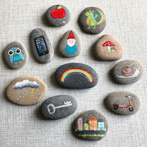 Set of stones with cute paintings like a gnome, mushroom, and rainbow.
