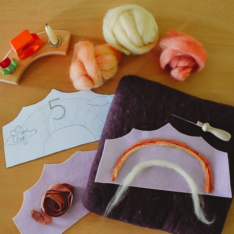 Sheet of felt cut into a crown shape laying on a needle felting mat with wool roving in pink, orange, and yellow 
