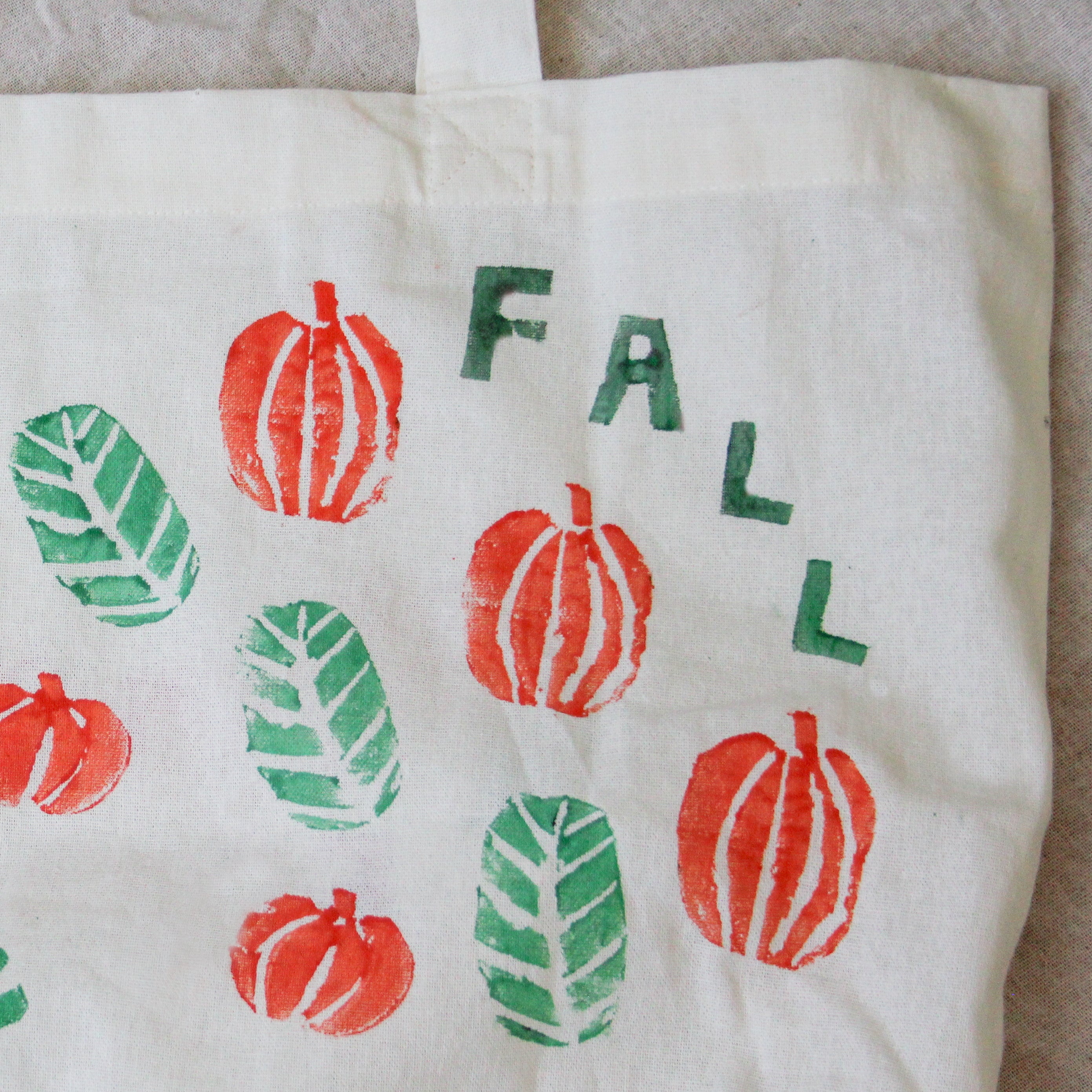 A potato printed bag says fall with leaves and pumpkins.