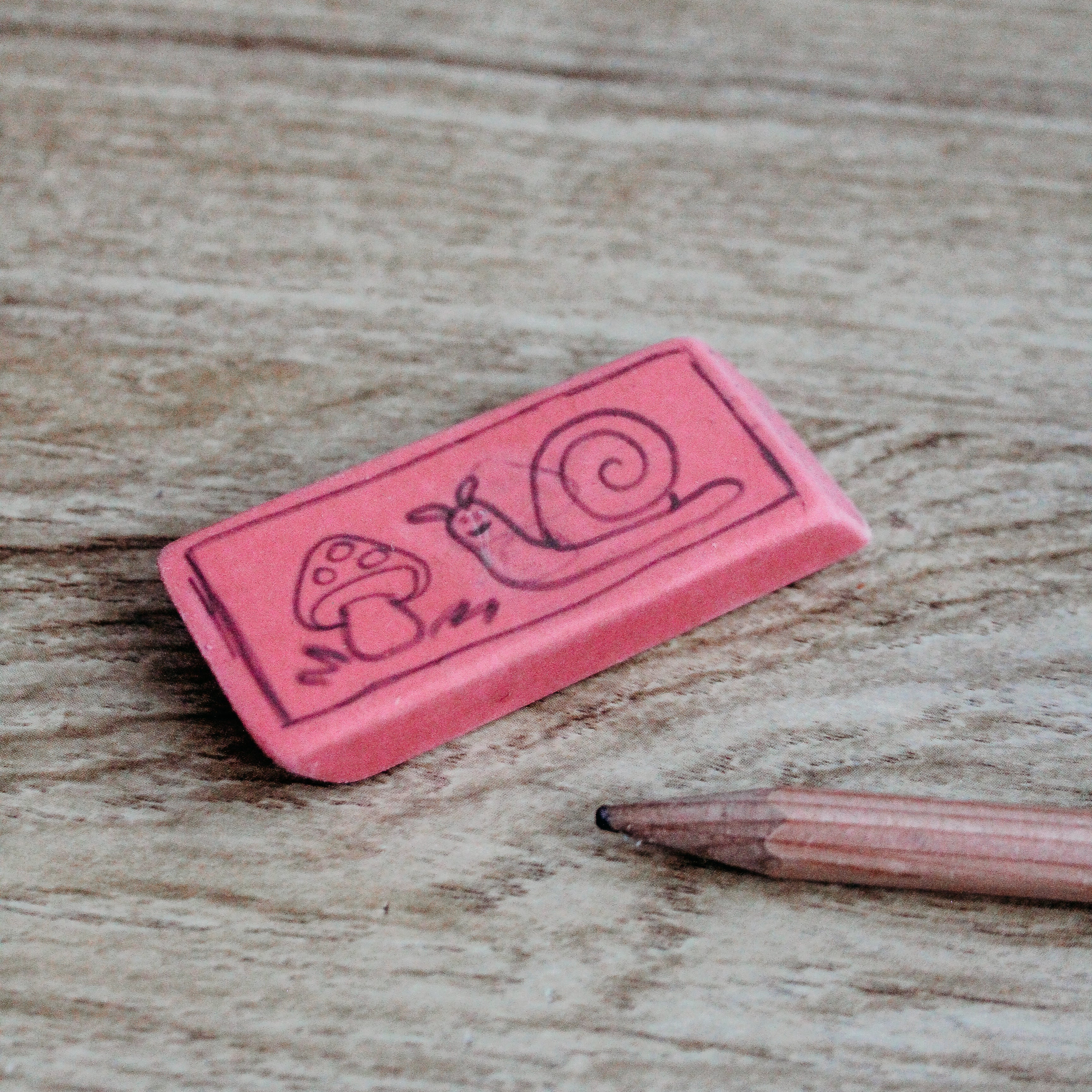 An eraser with a drawing on it sits ext to a pencil.
