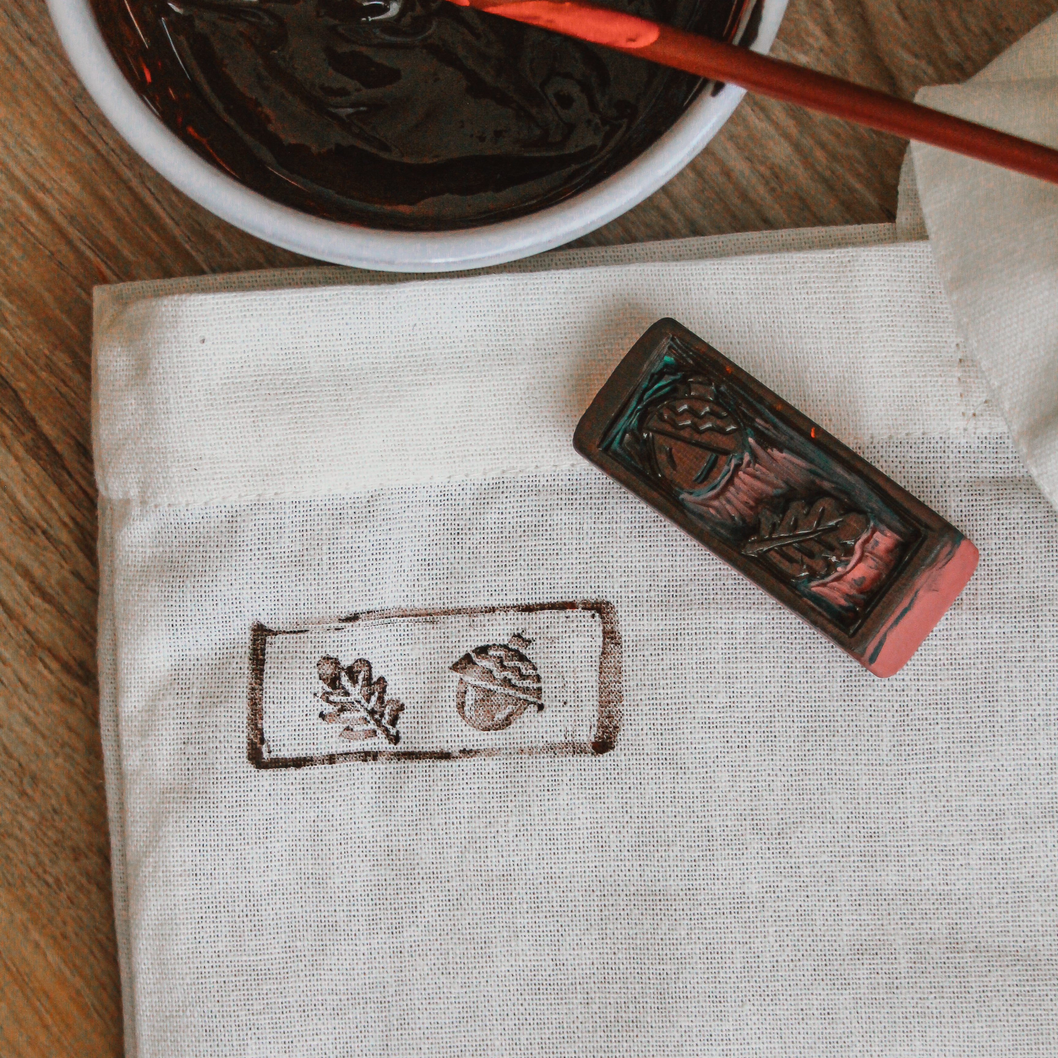 A carved stamp sits next to a freshly printed bag.