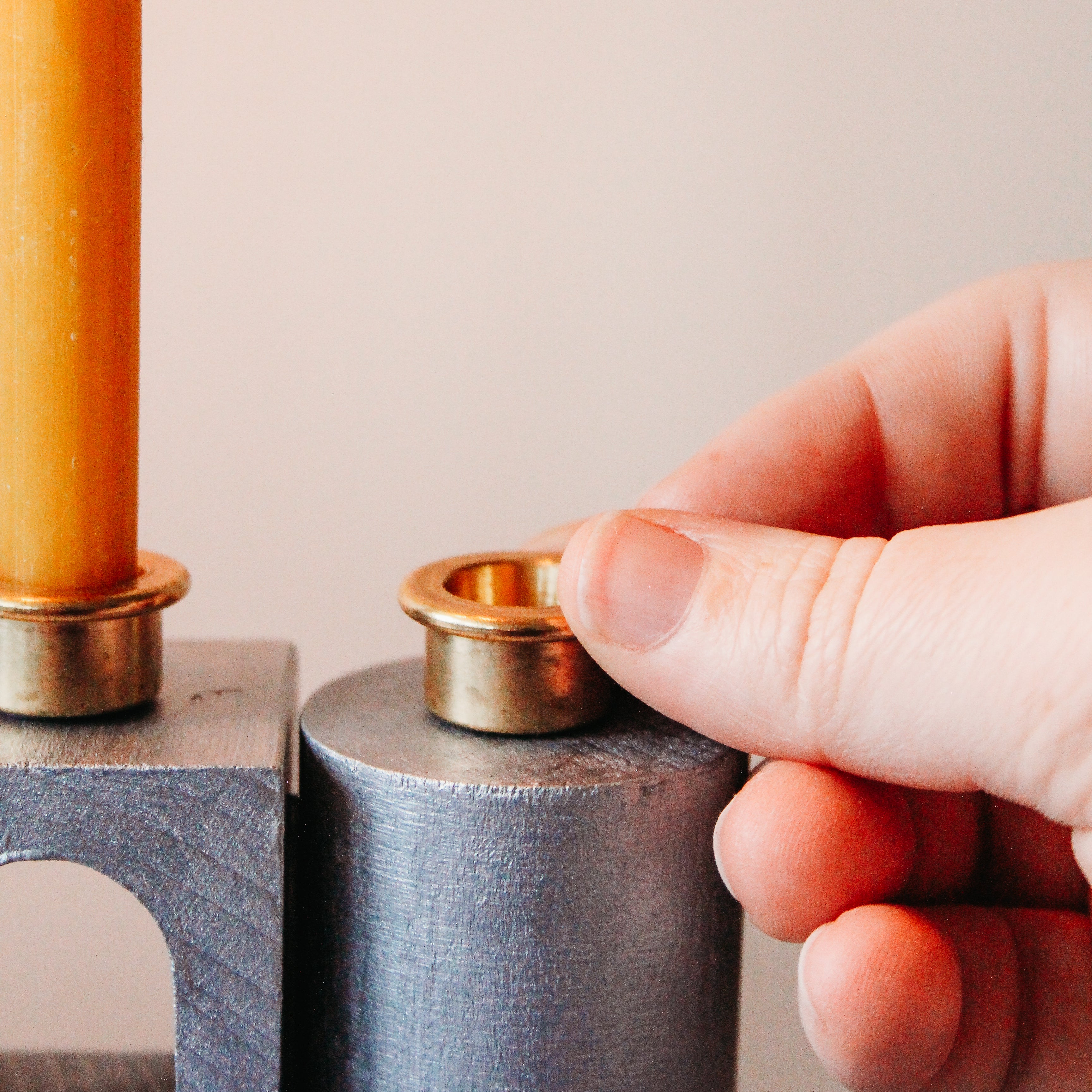 A hand is gluing on the brass candle holders to the painted HABA blocks.