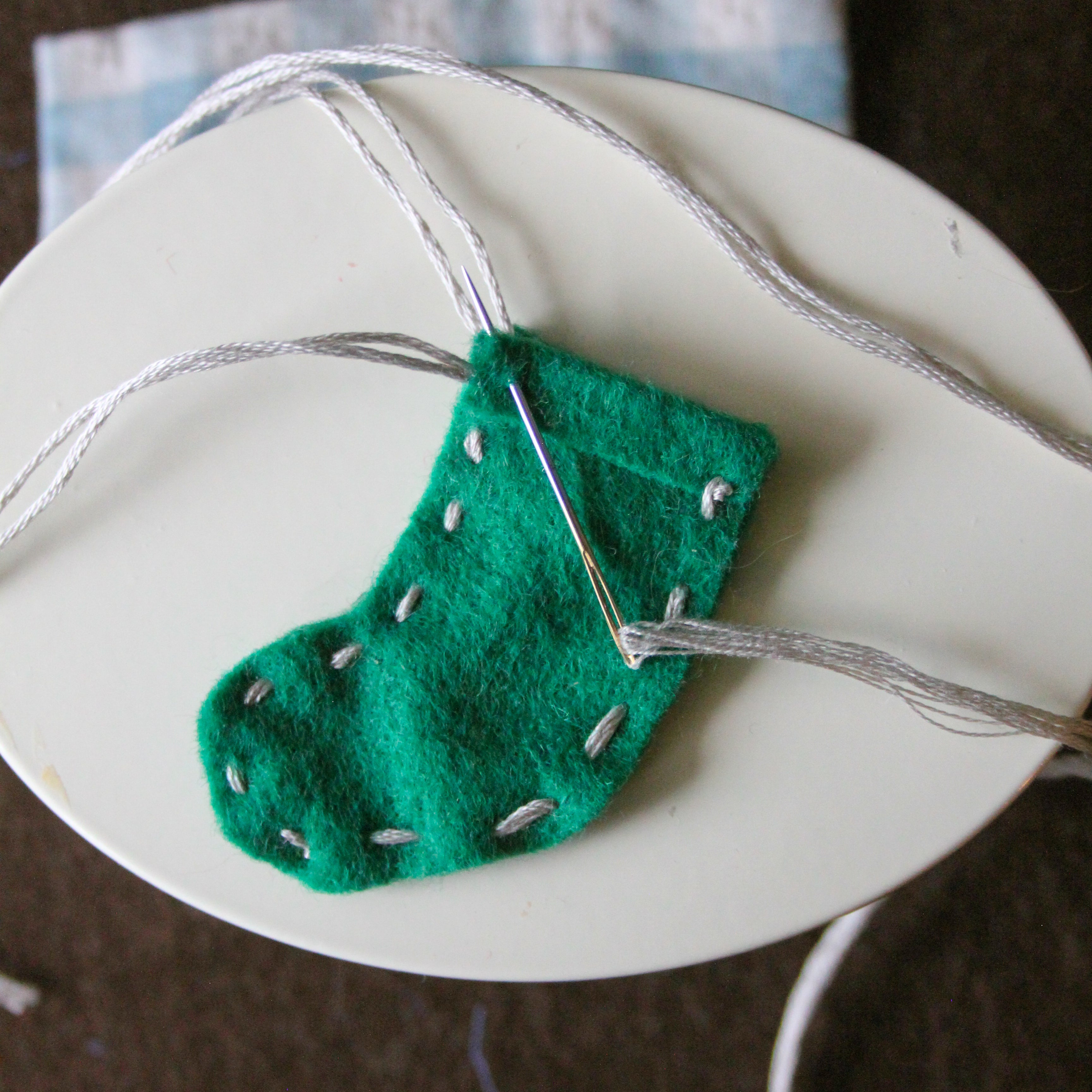 A felt stocking sits with embroidery thread on a Maileg table.