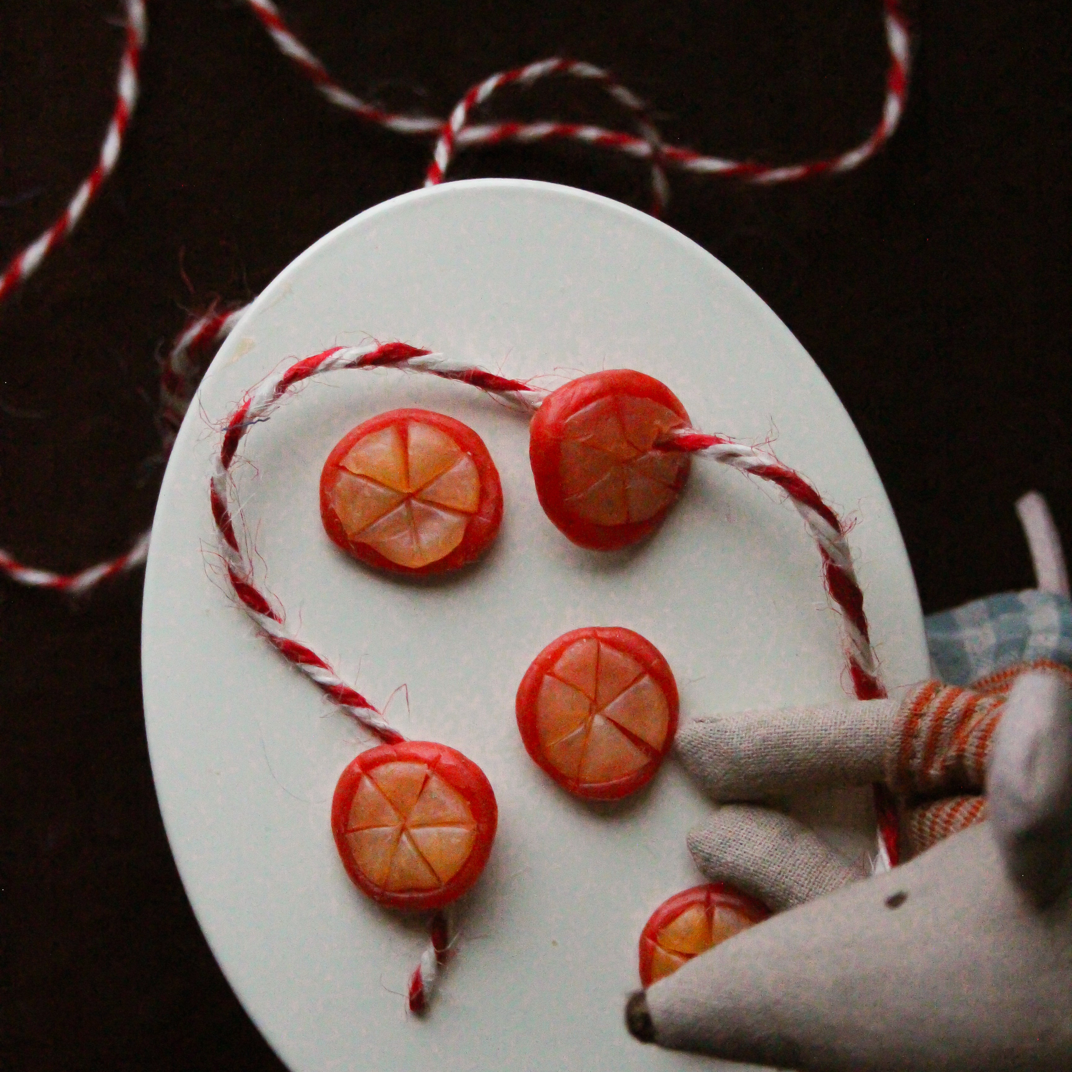 Beeswax oranges with twine sit on a white table.