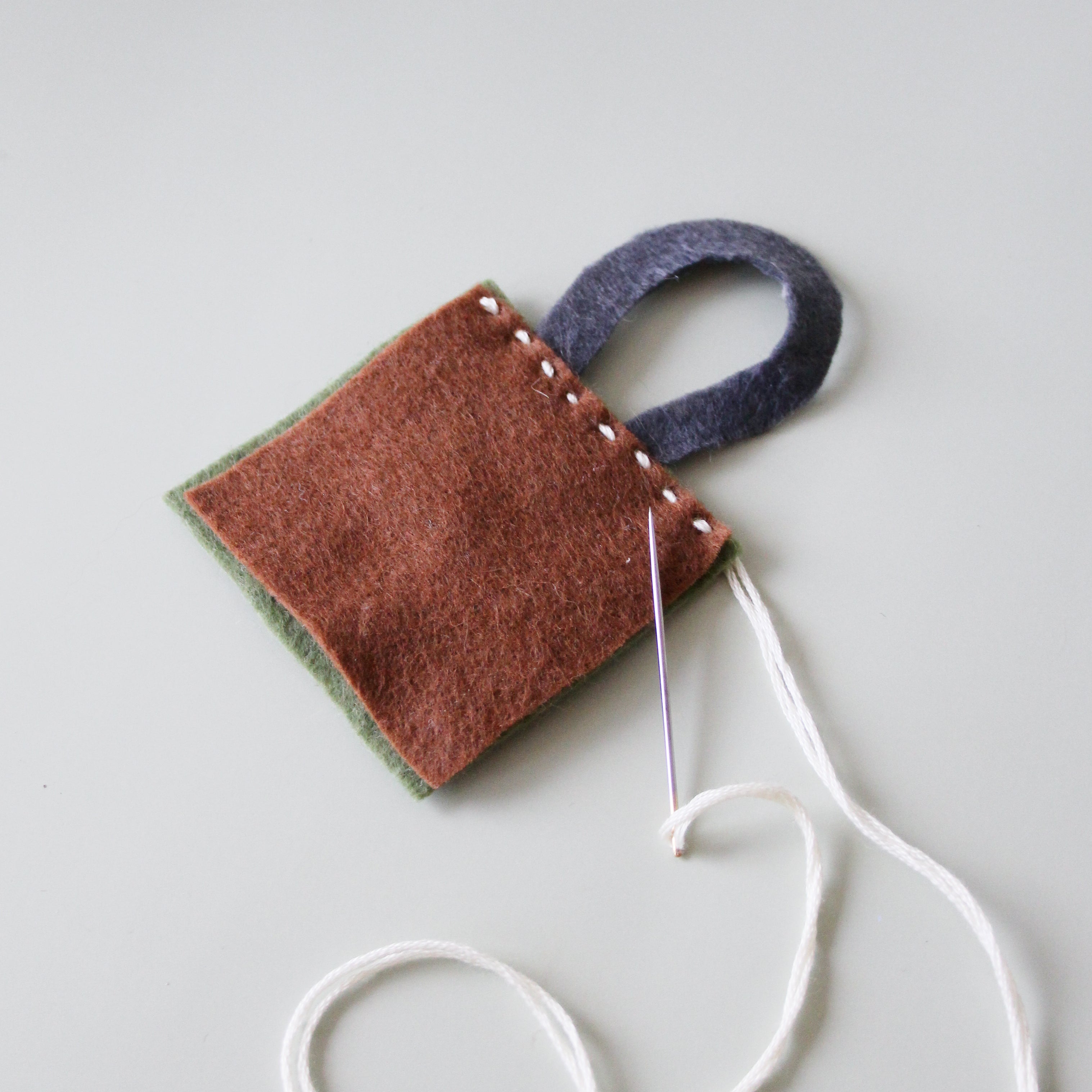 Two pieces of felt are being embroidered with a felt handle.