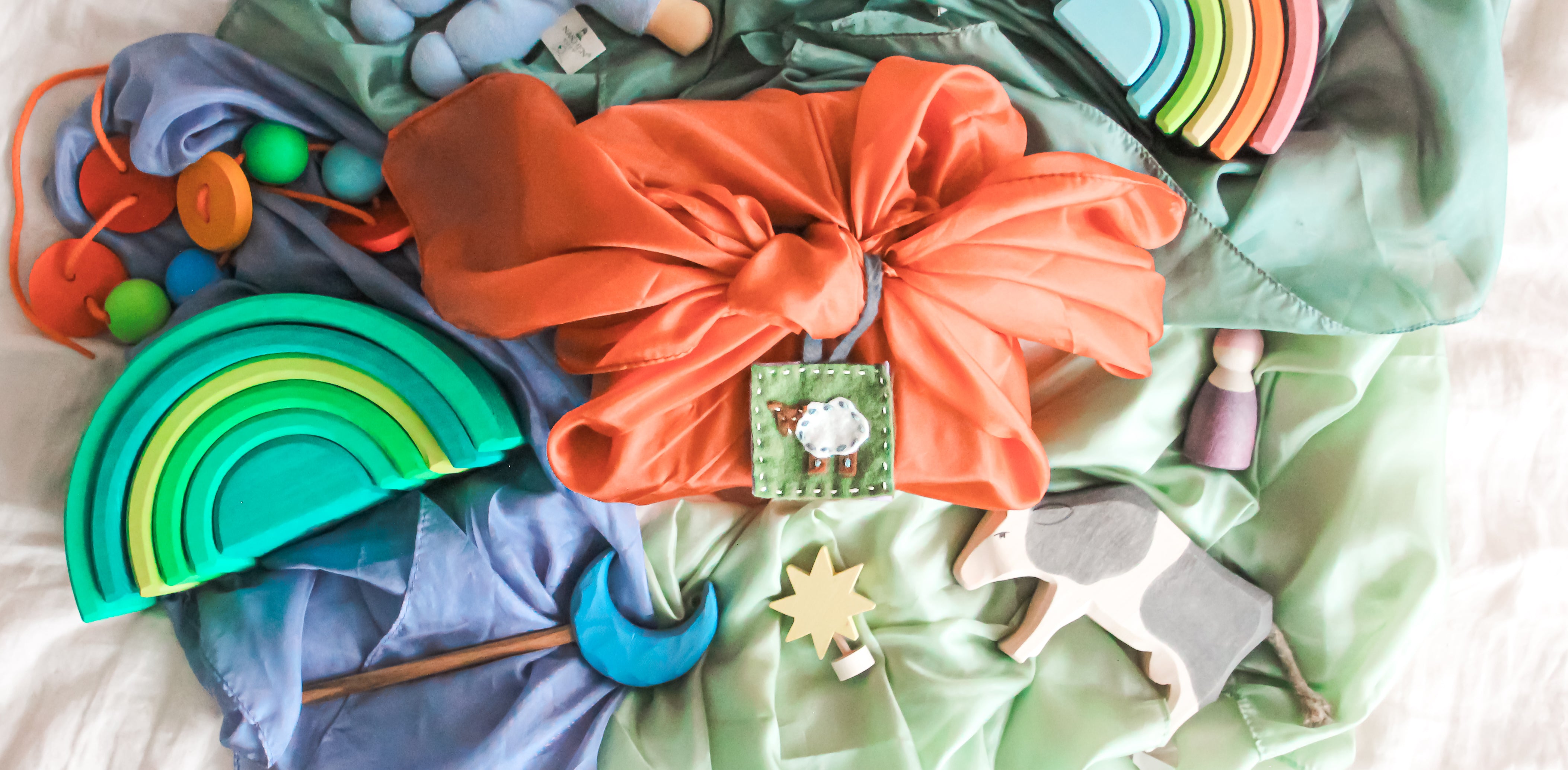 A felt tag sits on a silk wrapped gift with Waldorf gifts.