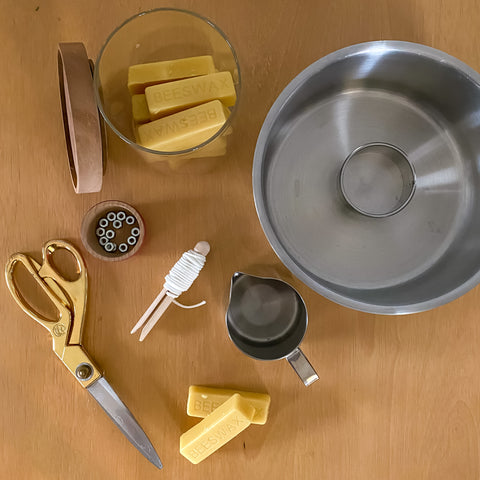 Ingredients to make hand dipped beeswax candles including beeswax, pot, metal pitcher, wick