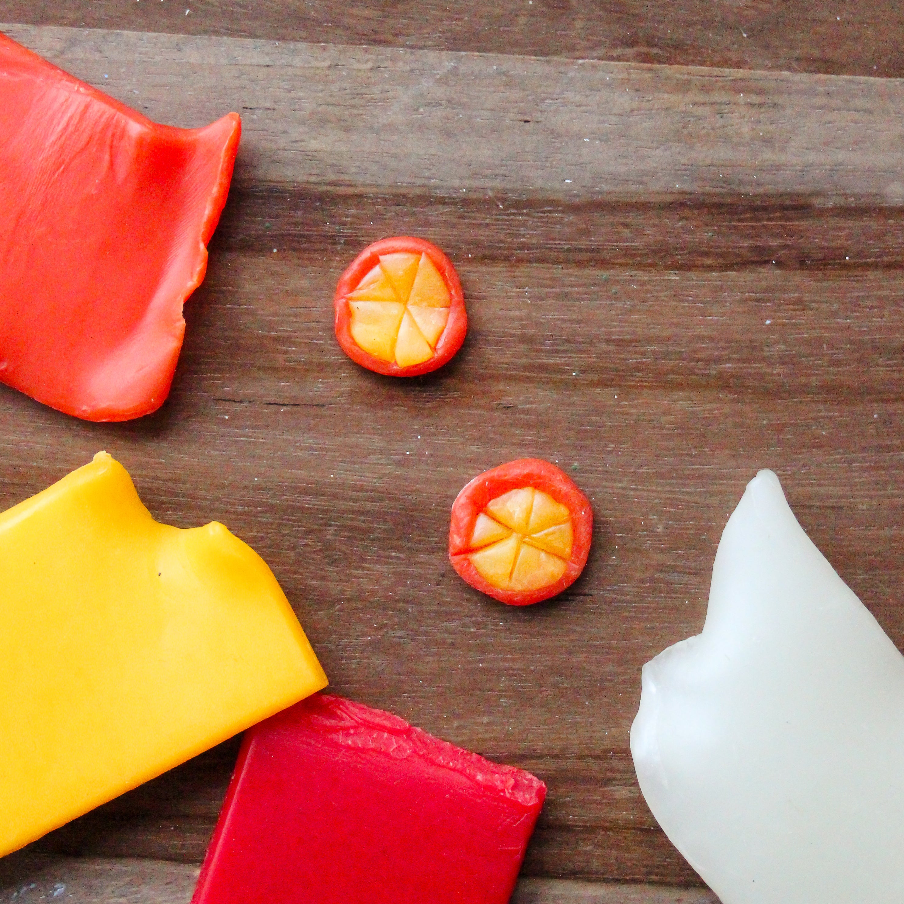 Beeswax oranges sit on a wooden table.