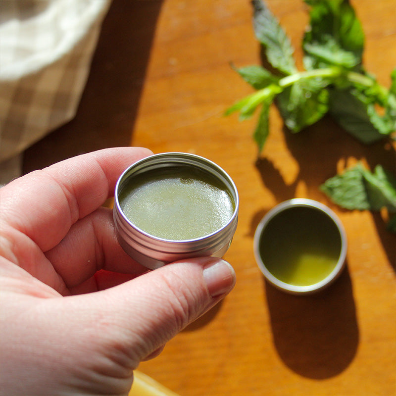 A hand is holding the beeswax lip balm.