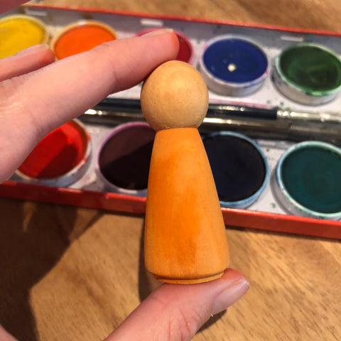 Wooden peg doll being painted orange with opaque water colors. Waldorf crafts
