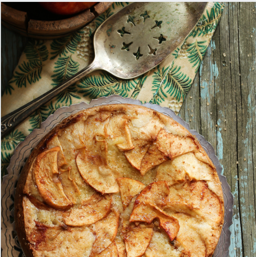 A homemade apple cake on a wooden table with a metal spoon
