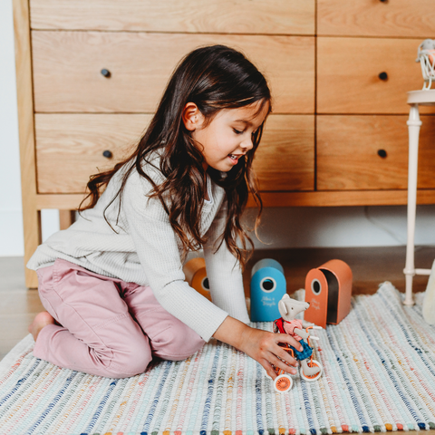 Child plays with a Maileg plush mouse on a tiny tricycle