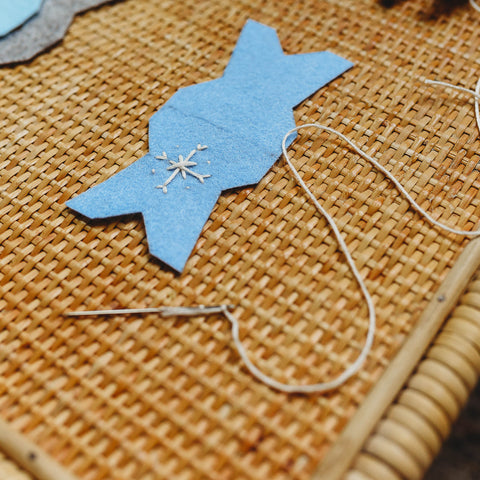 Tapestry needle and embroidery floss used to stitch a snowflake on the felt.