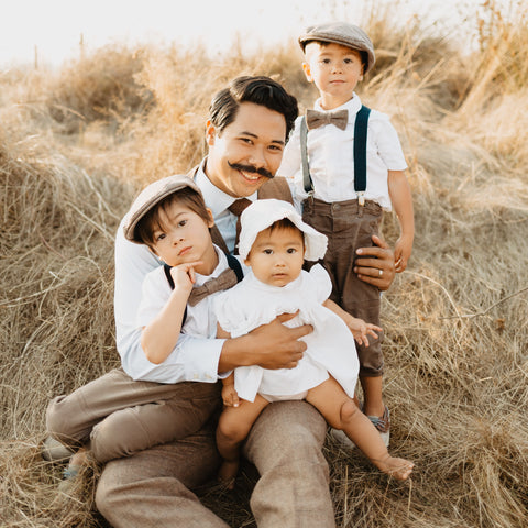 Father on a brown grassy hill with three children