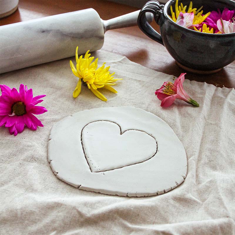 A heart shape is being cut out from the air dry clay.