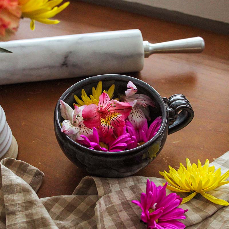 A mug sits filled with flowers.