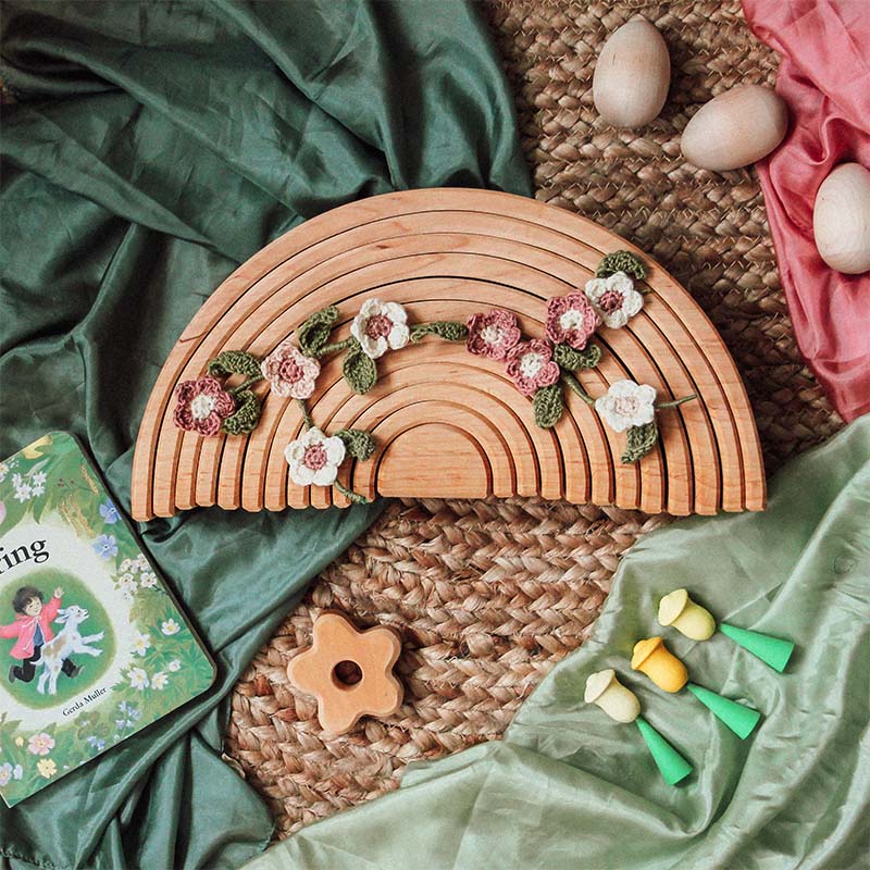 Crochet flower pattern on a wooden rainbow.