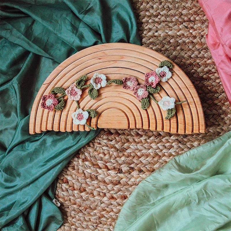 Crochet flowers on a wooden rainbow.