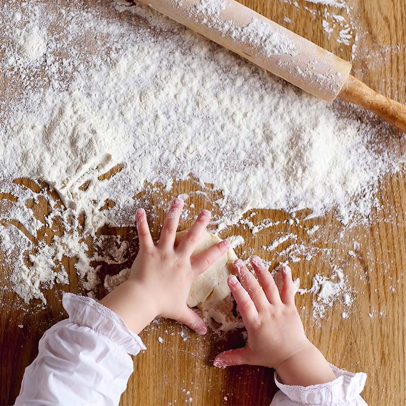 Small hands are kneading bread dough.