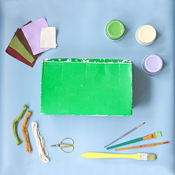 A collection of materials for the craft lay on a light blue background.