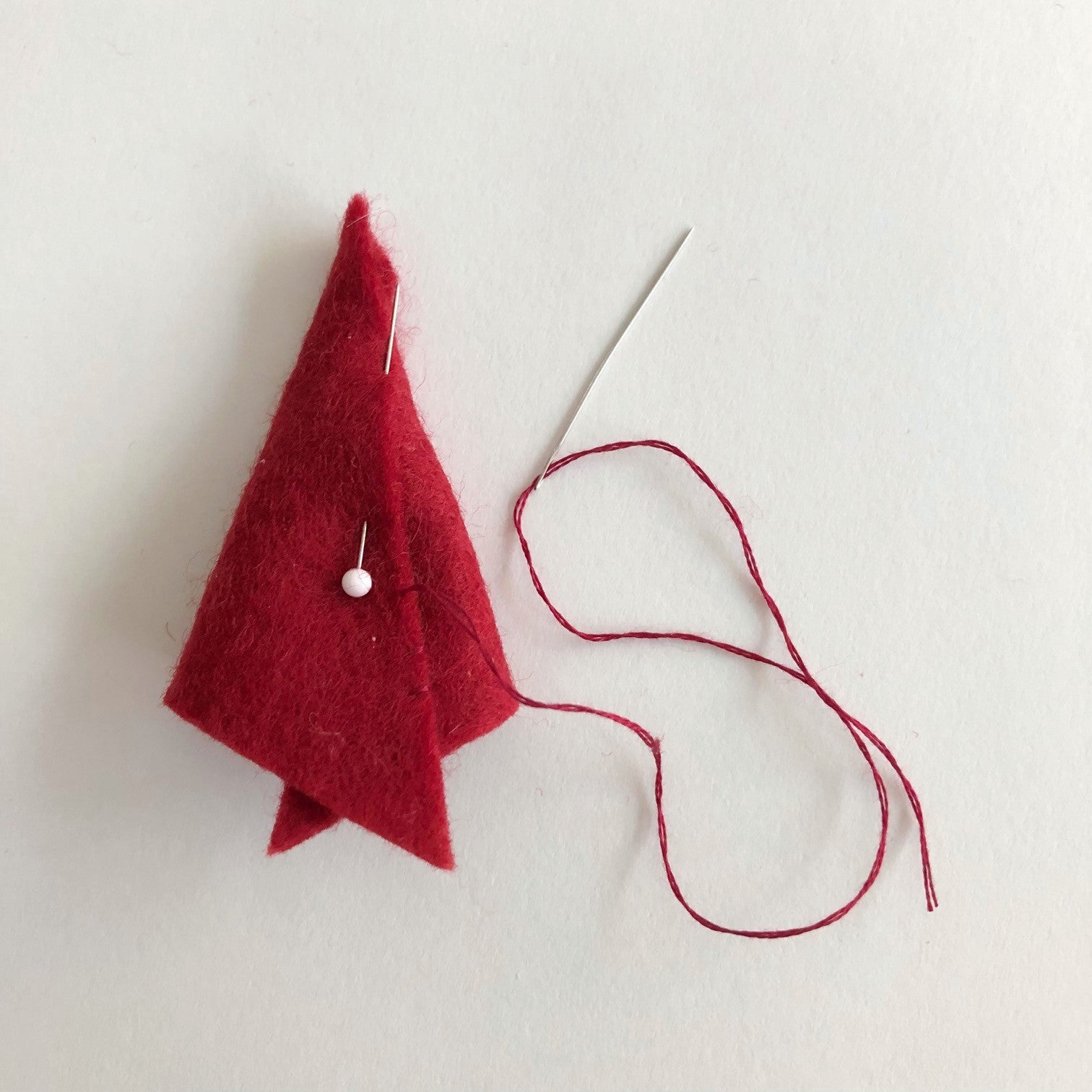 A handmade red felt hat next to a needle | Bella Luna Toys