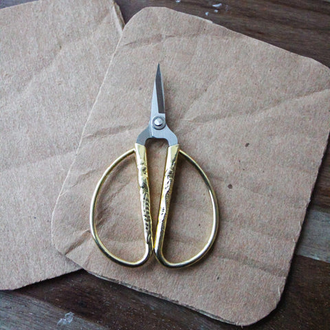 Cut cardboard sits with scissors on a table.