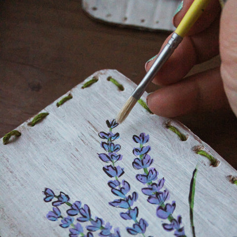 A Bella Luna upcycled card with lavender painted on it sits on a table.