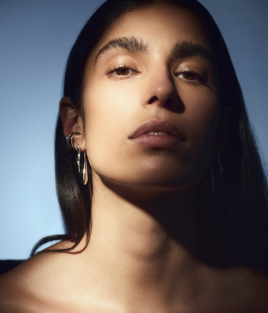 Close-up portrait of a person with long hair, wearing hoop earrings.