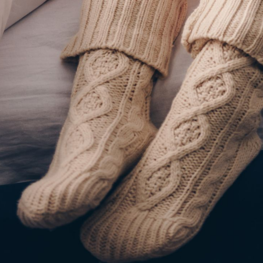 Image of person wearing cable knit socks in bed