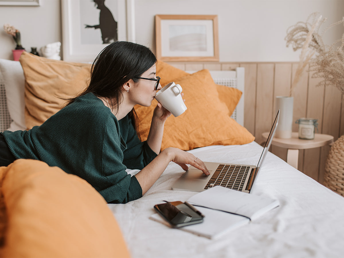 Woman using a laptop laying down in bed.