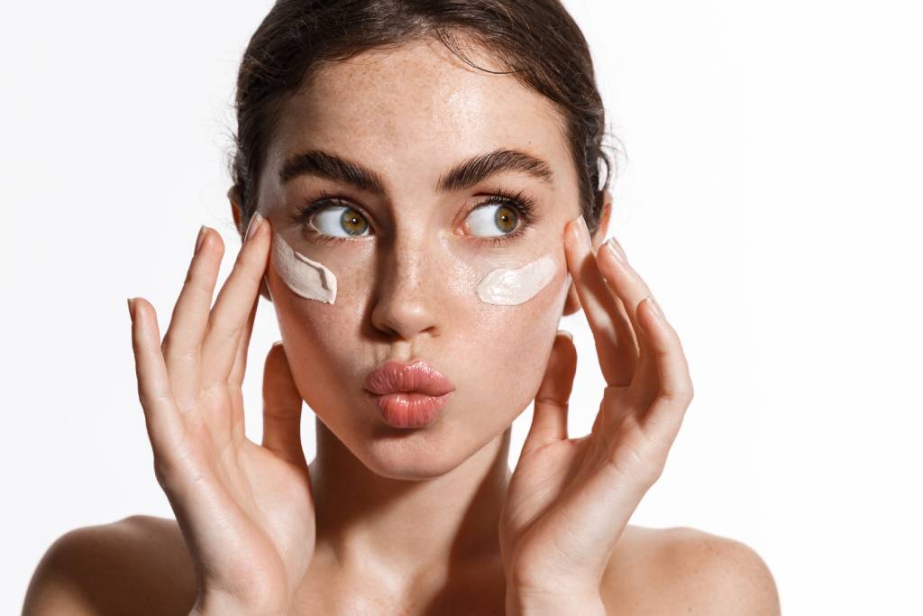 Woman applying moisturizer to dry cheeks