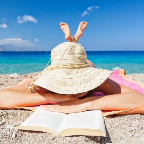 woman at the beach reading prep for sun exposure tips to take care of your skin