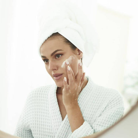 woman applying hydrating moisturizer to her skin in the morning