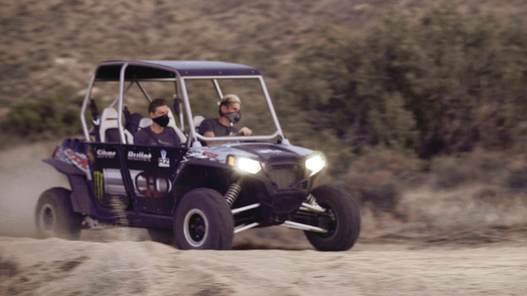 two men driving off-road in masks