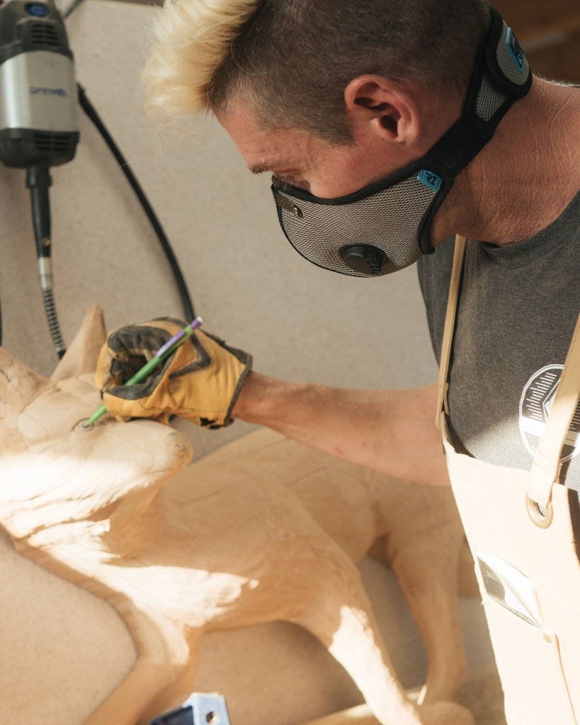 cory hamilton wearing RZ mask sanding wolf wood sculpture 