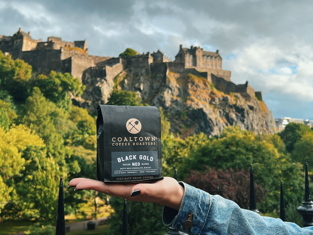 Bag of Black Gold being held in front of a castle in Edinburgh