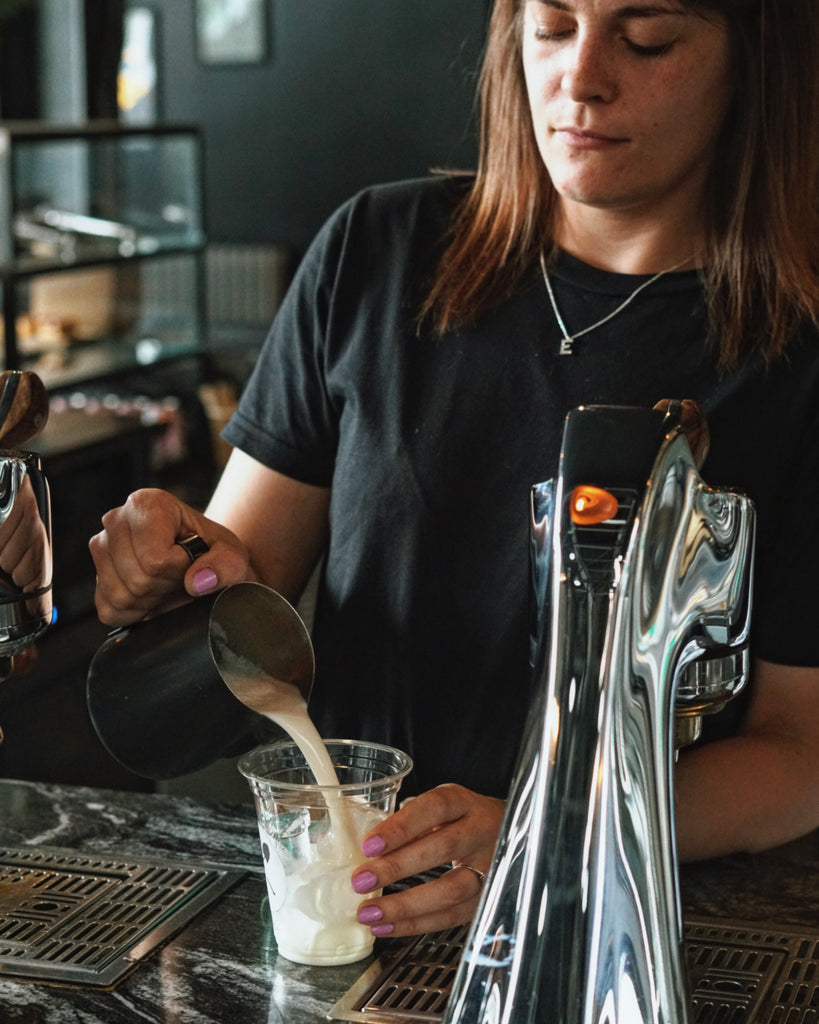 Steamed milk being poured over ice by our espresso bar team leader, Rhia