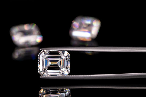 image of an emerald cut diamond held in a jewellers tweesers