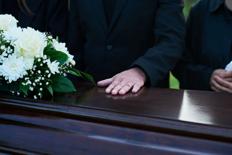 Man keeping hand on top of coffin